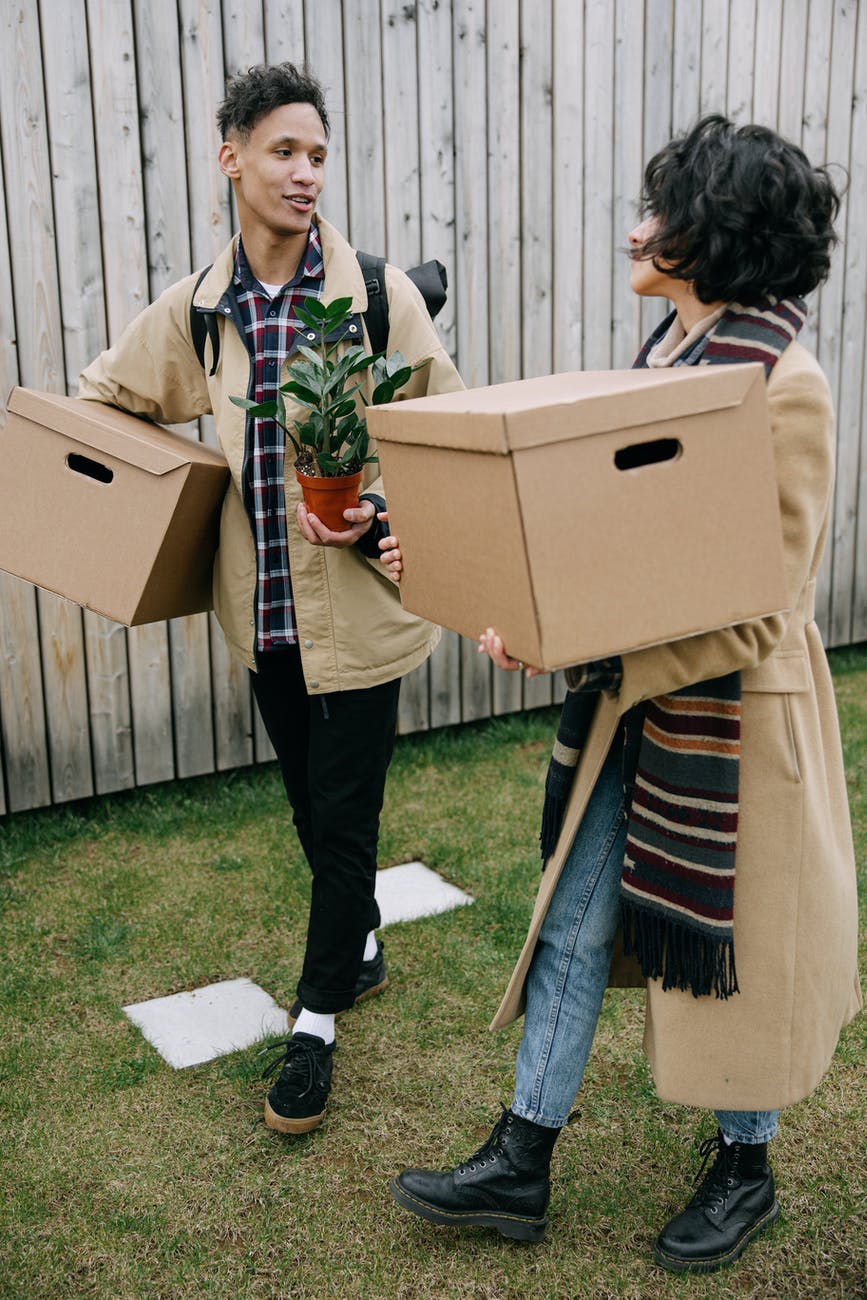 man and woman talking to each other while carrying cardboard boxes
